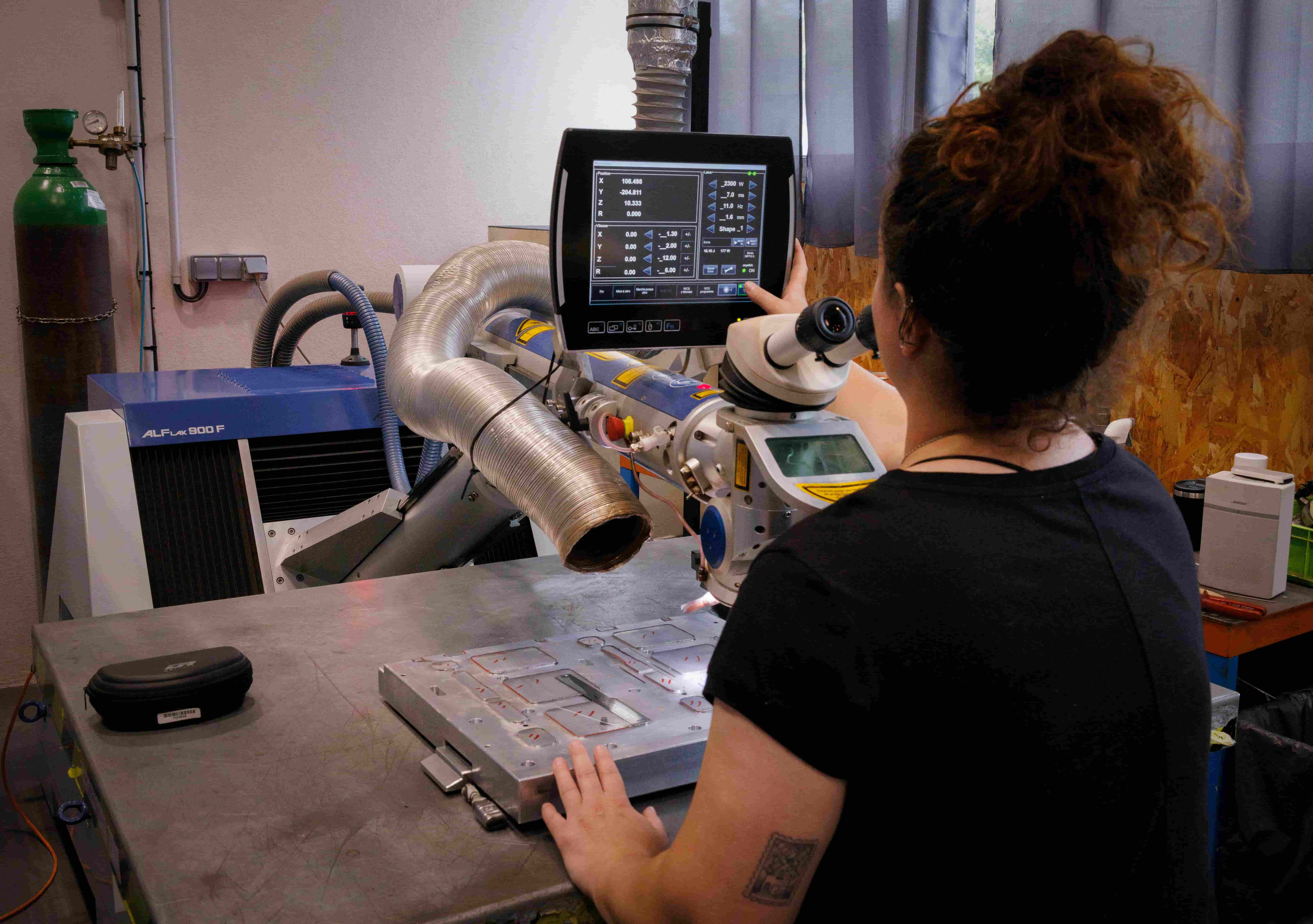 Technicienne utilisant une station de soudure laser pour la réparation d’un moule industriel